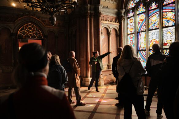 Eine Kulturvermittlerin zeigt auf die Glasbilder der Franzensburg.